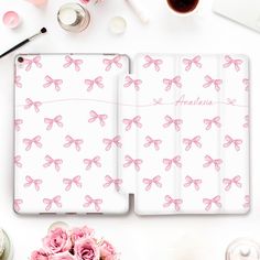 an ipad case with pink bows on it next to some flowers and other things around