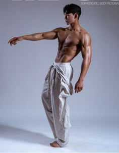 a shirtless man in white pants is posing for the camera with his hand on his hip