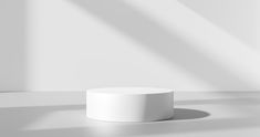 a white round object sitting on top of a table next to a shadow filled wall