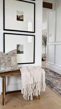 two framed pictures hang on the wall next to a wooden bench with a throw pillow