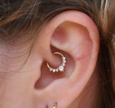 a close up of a person's ear with an earring in the shape of a crescent