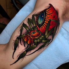 a man's arm with a colorful spider tattoo on it, and an eye in the center