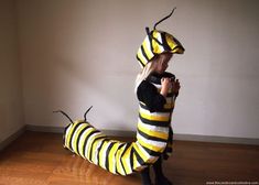 a woman in a costume made to look like a bee sitting on the floor next to a wall