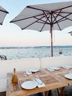 an outdoor dining area with tables and umbrellas over the water's edge at dusk