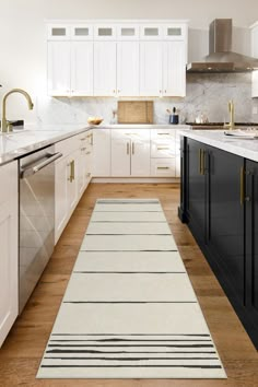 a kitchen with white cabinets and black counter tops, an area rug on the floor