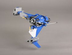 a blue and white toy airplane on a gray background with the propeller facing forward, it is made out of lego parts