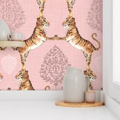 two tigers on pink wallpaper next to white vases and cups in front of it