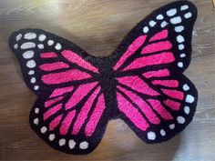 a pink and black butterfly rug sitting on top of a wooden table