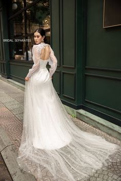 a woman in a wedding dress is standing on the street with her back to the camera