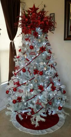 a white christmas tree decorated with red and silver ornaments