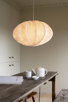 a light fixture hanging over a table with tea cups and coffee mugs on it