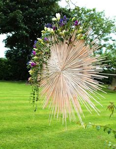 a sunburst made out of sticks and flowers in the middle of a field