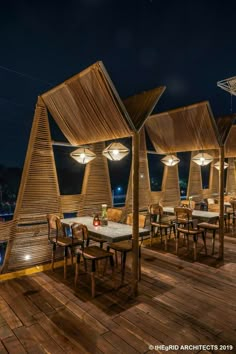 an outdoor dining area with wooden tables and umbrellas on the roof at night time