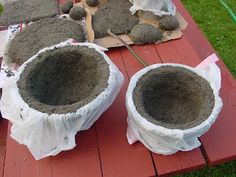 several cement pots sitting on top of a red picnic table covered in white cloths