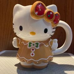 a hello kitty figurine sitting on top of a table next to a cup