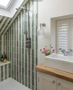 a white sink sitting under a window next to a bath tub in a room with green tiles on the walls