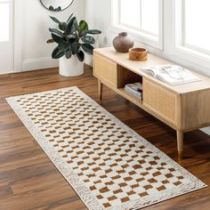 a white and brown rug sitting on top of a wooden floor next to a table