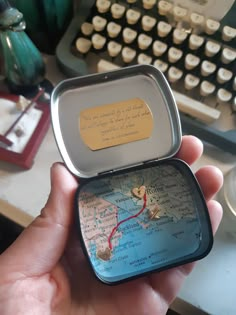 a person holding up a small map in front of an old typewriter with a note attached to it