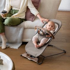 a woman sitting in a chair next to a baby with a cup on her lap