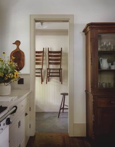 an open door leading to a kitchen with chairs and vases on the counter top