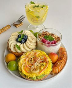 a white plate topped with food next to a cup of juice and a glass filled with liquid