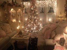 a living room filled with furniture and a christmas tree in front of a window covered in lights