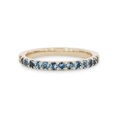 a yellow gold band with blue topaz stones on the inside and outside, set against a white background