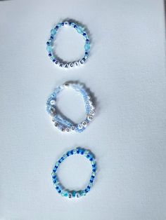 three beaded bracelets sitting next to each other on a white surface with blue beads