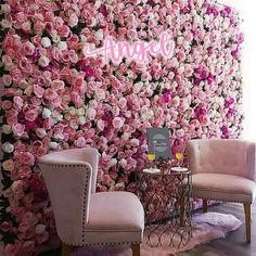 two chairs and a table in front of a wall with pink flowers on the walls