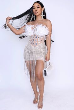 a woman in a white dress and feathers on her head is posing for the camera