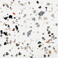 a white wall with lots of black and brown rocks on the top of it's surface