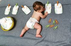 a baby laying on top of a blanket next to some carrots and paper towels