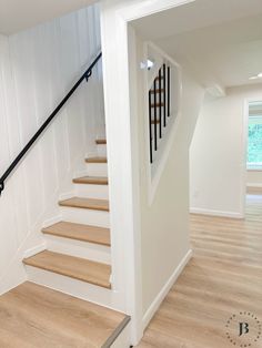 an empty room with white walls and wood floors, stairs leading up to the second floor