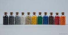 a row of glass bottles filled with different colored candies next to each other on a white surface