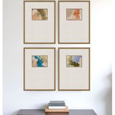 four framed pictures hang on the wall above a table