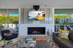 a living room with couches, chairs and a television mounted on the wall over a fireplace