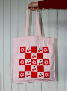 Pack up a picnic in this vibrant pink tote bag, displaying a checkerboard of cherries and cherry blossoms. It's the perfect accessory for spring! Totes are made of 12 oz cotton with self-fabric handles. They're very sturdy, you don't have to worry about overloading or ripping these. They measure a solid 10 inches wide by 13 1/2 inches high and expand to about 5 inches deep. Machine washable, tumble dry, iron as needed, bleach not recommended. Picnic Tote, Pink Tote Bag, Pink Tote Bags, Pack Up, Pink Tote, Foodie Gifts, Kids Hats, Food Gifts, A Picnic