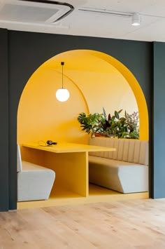 an office with yellow and grey walls, wooden floors and a circular bench in the center