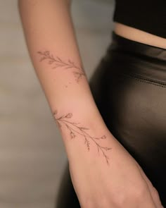 a woman's arm with a tattoo on it that has leaves drawn on it