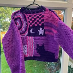 a purple sweater hanging on a window sill