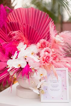 a pink fan and some flowers on a table