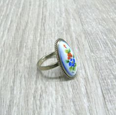 "Finift enameled jewelry, USSR vintage ring with enamel painting, retro statement ring for woman, her anniversary gift, Red poppy and blue cornflower ring. This Russian hand painted enamel ring features red Poppy flower along with blue cornflower, surrounded with green leaves on baby blue background Size: 6 1/2 ( US and Canada ), N, O 1/2, Q( UK and Australia ), 17, 17 1/4, 18 ( European ). The enamel painted oval cabochon is 10 mm wide and 22 mm long. It is set in silver tone metal cast with a Antique Enamel Ring As A Gift, Vintage Flower Shaped Rings For Gift, Handmade Retro Rings As Gift, Antique Round Enamel Ring For Gift, Antique Round Enamel Ring Gift, Vintage Oval Enamel Ring Gift, Vintage Blue Enamel Rings, Handmade Vintage Style Enamel Ring, Vintage Handmade Flower Ring As Gift