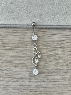 an image of a dangling belly ring with three stones on it's back end