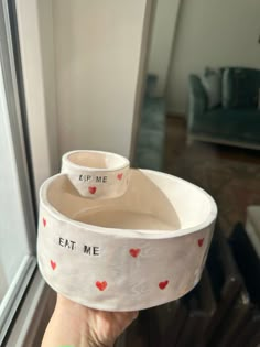 someone is holding up a bowl that says eat me and two bowls with hearts on them