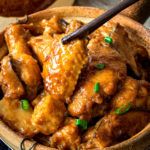 a wooden bowl filled with chicken and green onions