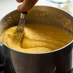 a person whisking something in a pot on the stove