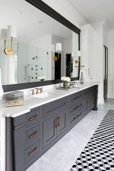 a large bathroom with black and white tile flooring, two sinks and mirrors on the wall