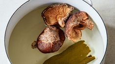 three mushrooms are in a white bowl with some green liquid on the floor next to them