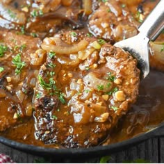 meat and onions are being cooked in a skillet with a ladle on the side