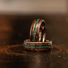 two wedding bands with green and brown wood inlays on top of each other